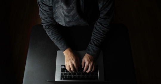 A person in a dark room typing at a computer