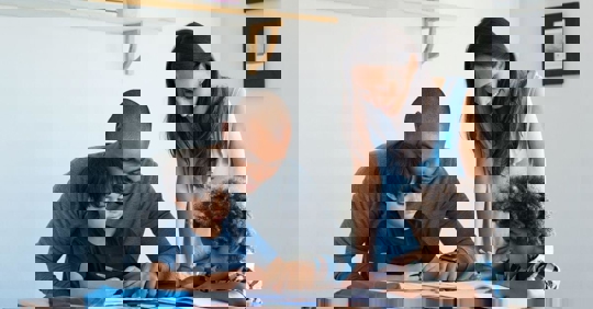 A father and mother sitting with their two sons; they appear to be planning something.